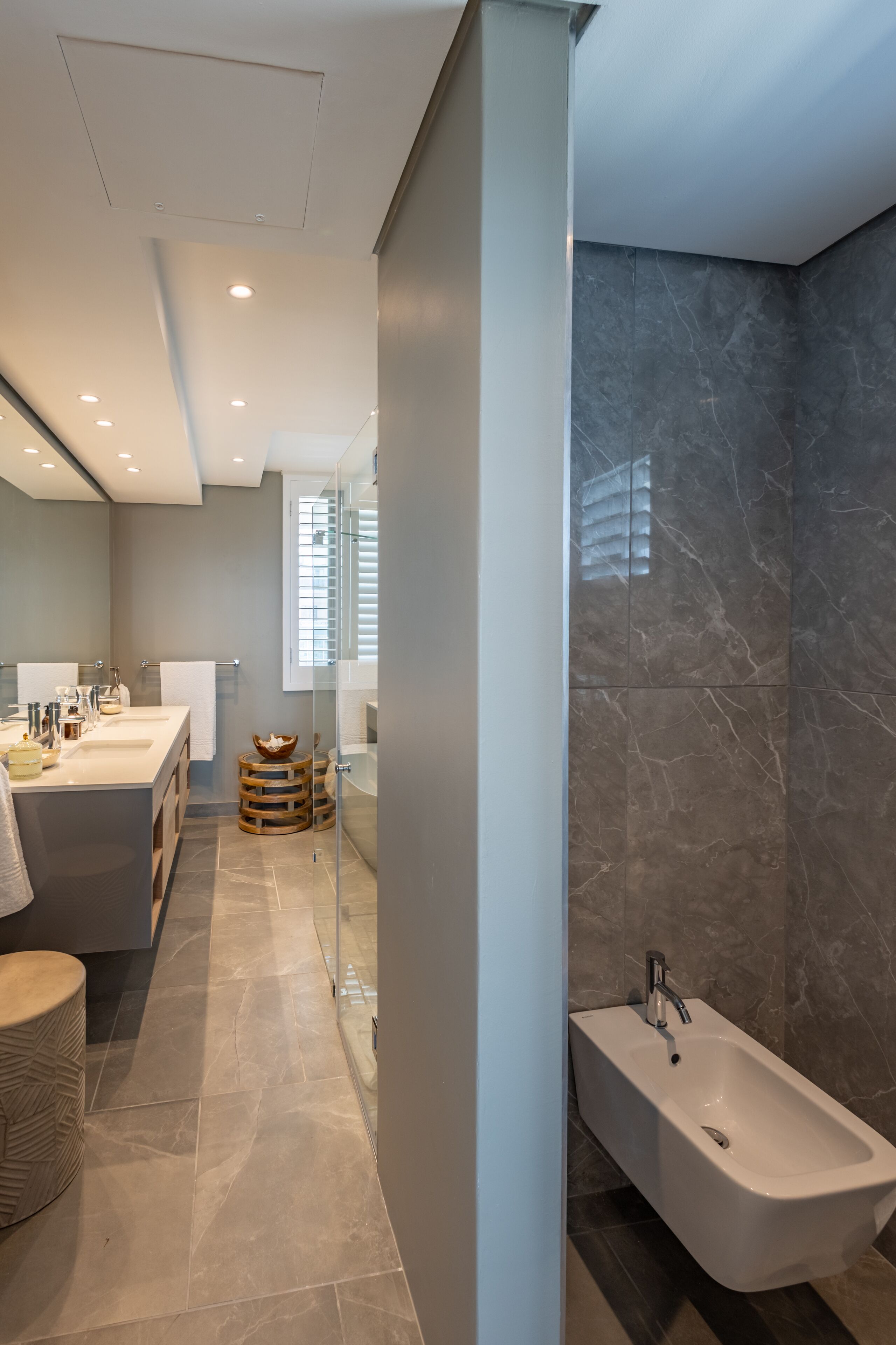 A modern bathroom with a large mirror, two sinks, a bathtub, and a glass shower enclosure.