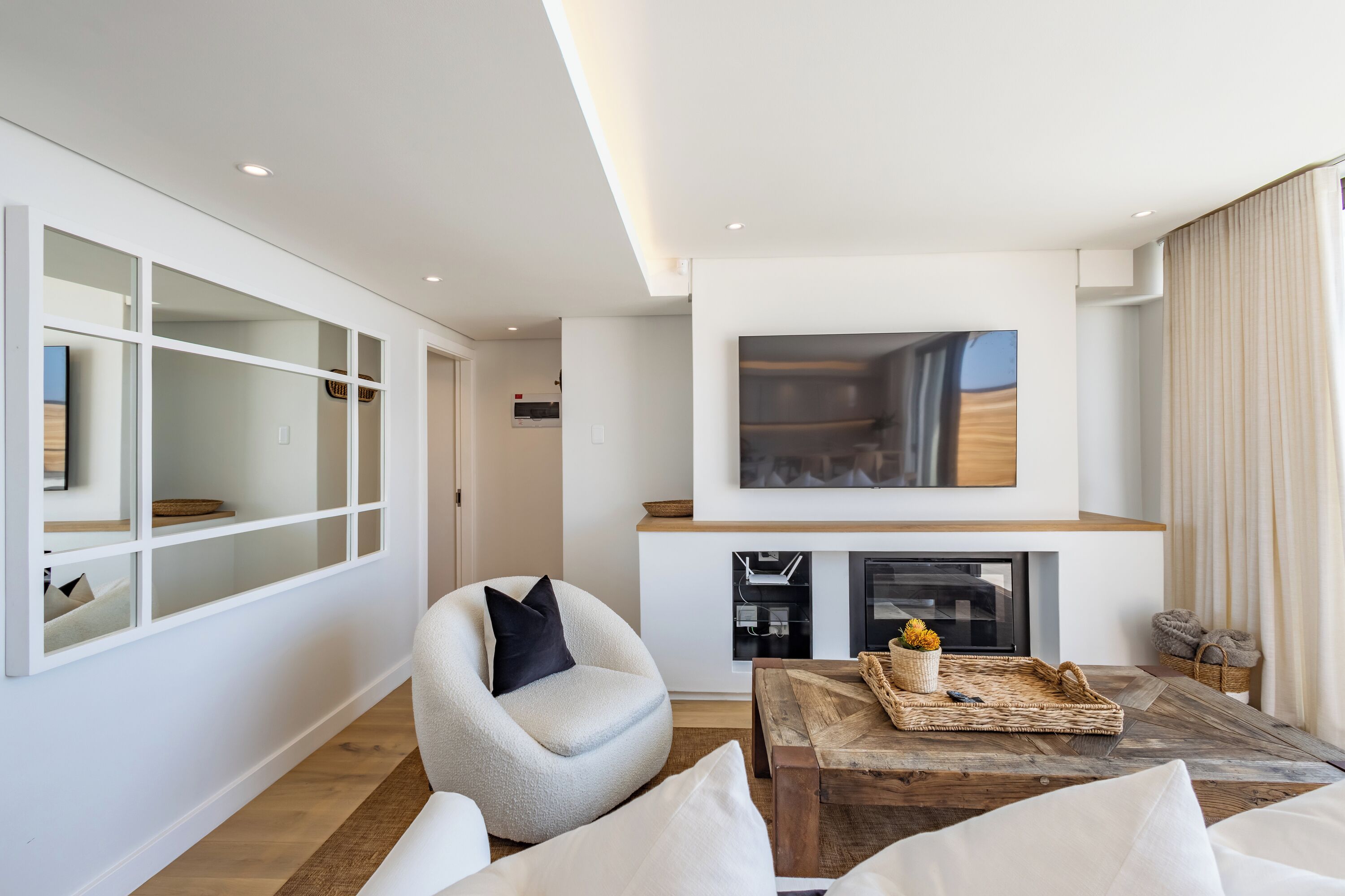 A modern living room with a fireplace, a comfortable armchair, and a wooden coffee table.