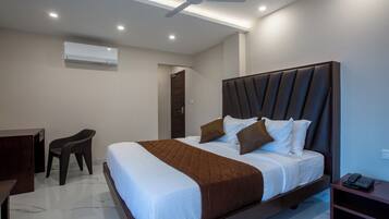 Una habitación de hotel moderna con una cama grande, un escritorio, una silla y un ventilador de techo.