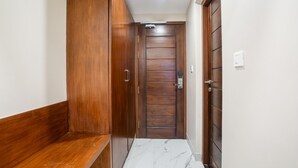 A hallway with wooden doors and a marble floor. - PARKKAVAN TOWERS (Manachanallur)