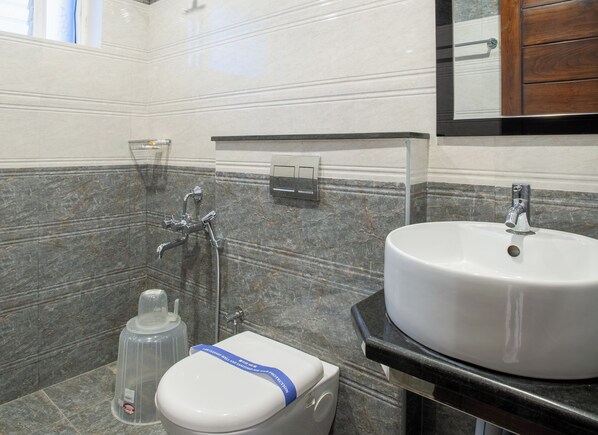A bathroom with a white toilet, a sink, and a shower. - PARKKAVAN TOWERS (Manachanallur)