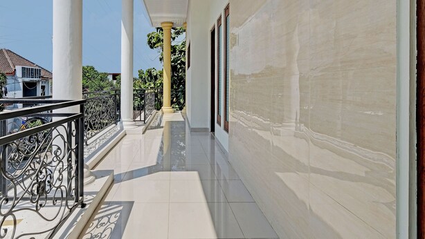 A covered balcony with white columns and a tiled floor. - OYO Life 92935 Ayu Kost Eksklusif (Ngaglik)