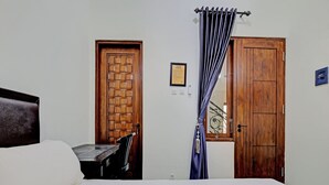 A bedroom with a bed, a wooden door, a chair, and a curtain. - OYO Life 92935 Ayu Kost Eksklusif (Ngaglik)