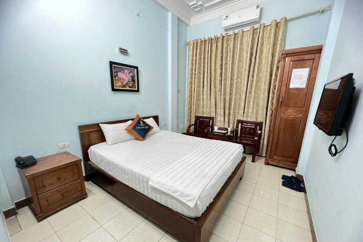 Une chambre à coucher comprenant un lit, une table de chevet, une chaise, un téléviseur et une armoire.