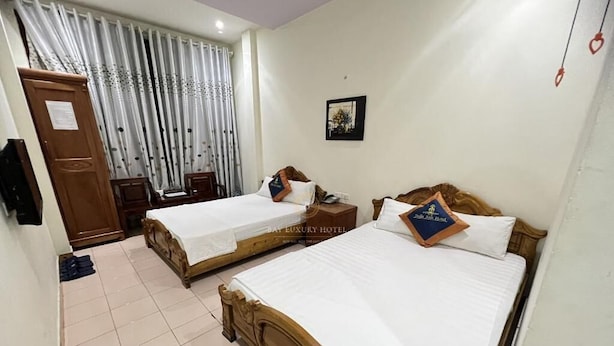 Una habitación de hotel con dos camas individuales, un armario de madera, un escritorio y una silla.