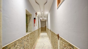 Un couloir aux murs blancs, doté d’un sol à motifs et d’un plafond pourvu d’un éclairage encastré.
