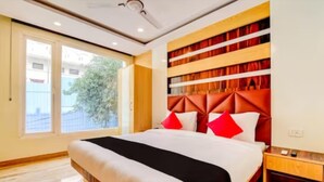Une chambre d’hôtel moderne avec un grand lit, une tête de lit en bois et une vue sur l’extérieur.