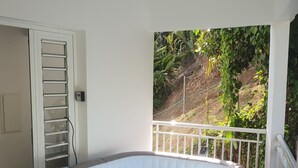 Un jacuzzi sur un balcon avec vue sur la verdure et une balustrade blanche.