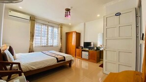 Una habitación de hotel con cama, televisor, armario y escritorio con silla.