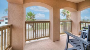 A covered outdoor area with a wooden bench and a view of the ocean. - Walk to the Beach | Golf Cart Rental, Beach Boardwalk, Balcony Views | AvantStay (Port Aransas)