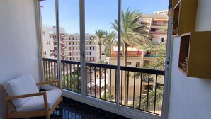 A balcony with a white chair, a view of a residential area with buildings and palm trees. - Guayero 2 (Los Cristianos)