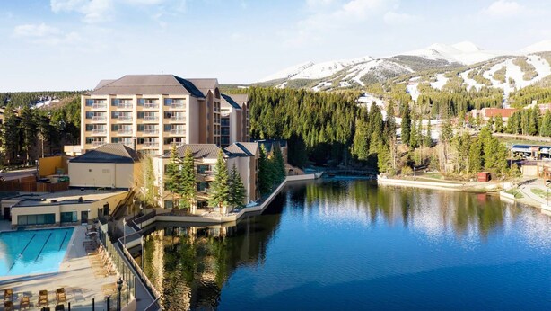 A hotel with multiple floors, a swimming pool, and a view of a lake and mountains. - Ski-in Ski-out - Family Friendly - Sleeps 6 - Marriott's Mountain Valley Lodge (Breckenridge)