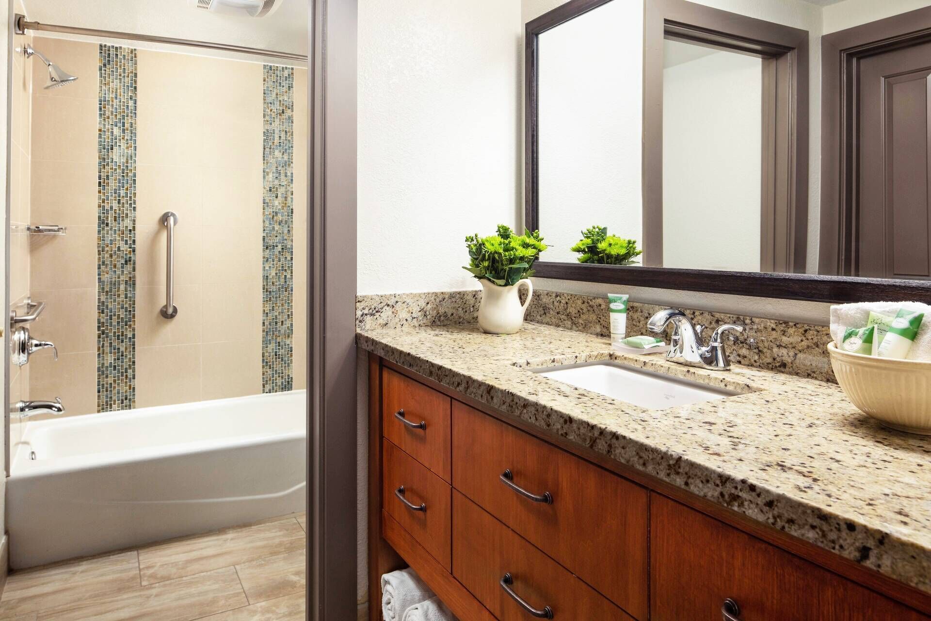 A bathroom with a bathtub, a sink, a mirror, and a shower area.