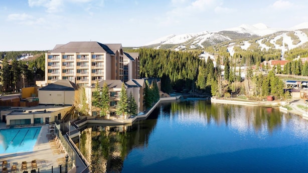 Un hôtel à étages, doté d’une piscine et offrant une vue sur un lac et des montagnes.