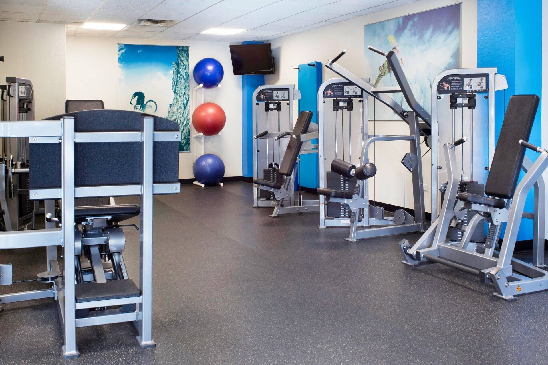 Ett gym med olika träningsmaskiner, en vattenautomat och träningsbollar.