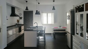 Une cuisine moderne dotée d’un îlot central, de luminaires suspendus, d’une cuisinière encastrée et d’un réfrigérateur.
