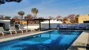 Une piscine dotée de chaises longues, d’une pergola et d’un mur carrelé orné d’œuvres d’art.