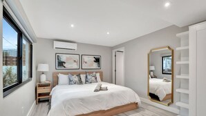 A modern bedroom with a large bed, bedside tables, a mirror, and artwork on the wall. - Lux Villa - 3br/2ba off Las Olas (Fort Lauderdale)