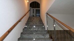 Un escalier avec des marches en marbre, des rampes en bois et une balustrade en verre.