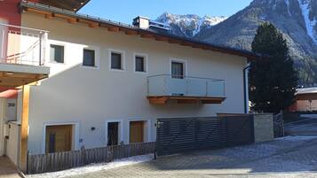 A two-story building with a balcony, a wooden fence, and a mountain backdrop.