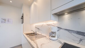 Een moderne keuken met een marmeren aanrechtblad, een inbouwspoelbak, een koffiezetapparaat en een zwart inductiekooktoestel.