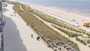 Een hotel aan het strand met een lange promenade, terras en uitzicht op zee.