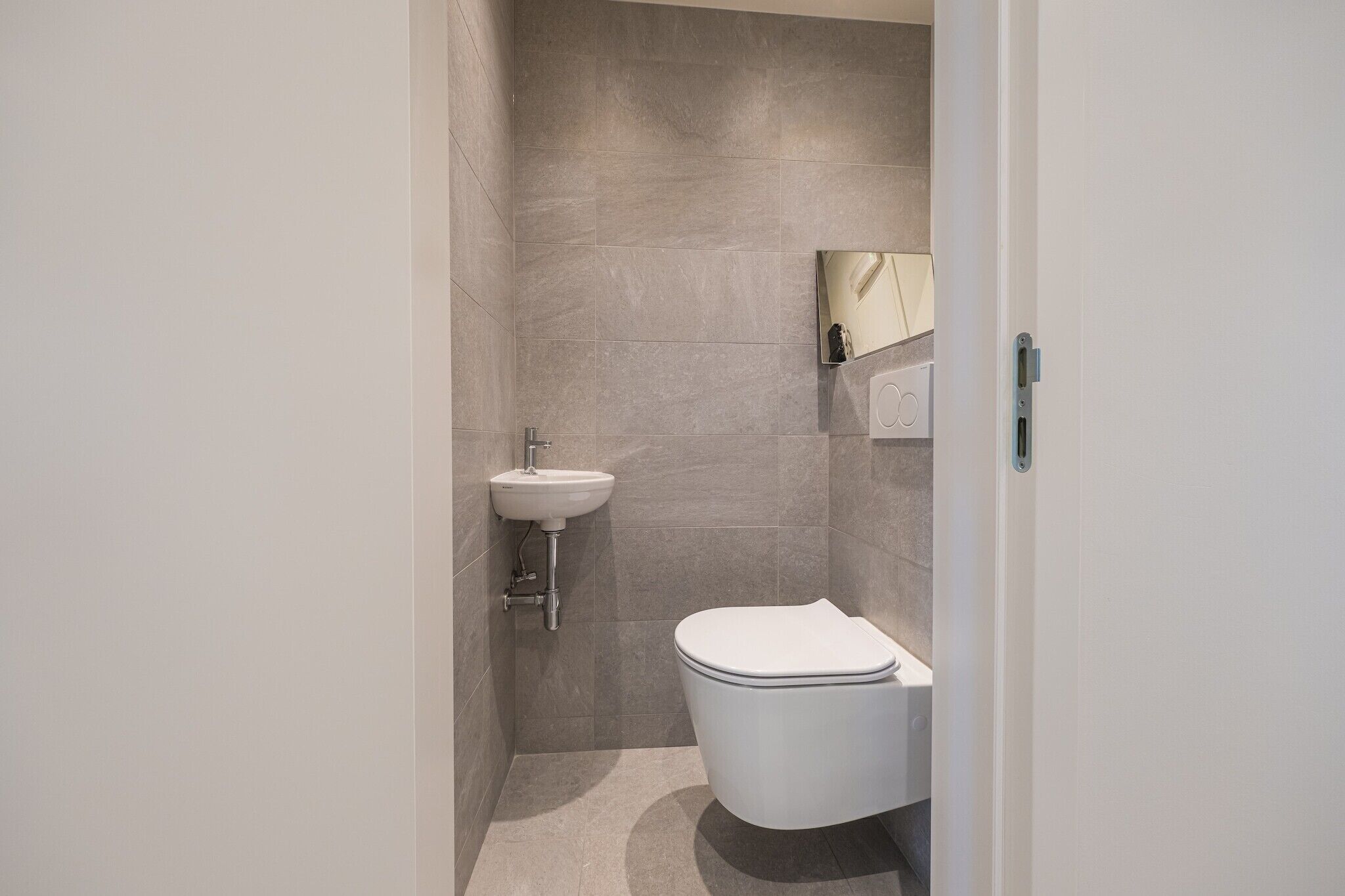 A modern bathroom with a white toilet, a sink, and a mirror.