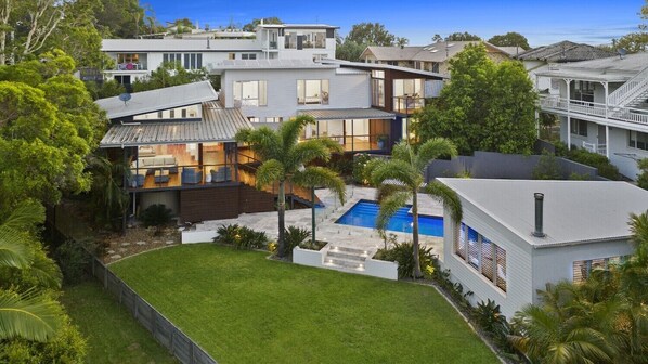Une maison moderne dotée d’une piscine, d’un patio couvert et d’une pelouse bien entretenue.