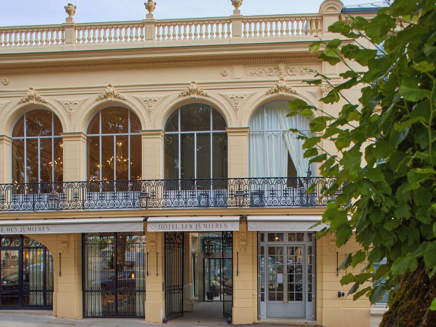 Ein historisches Gebäude mit aufwendiger Architektur, großen Bogenfenstern und einem Balkon mit schmiedeeisernen Geländern.