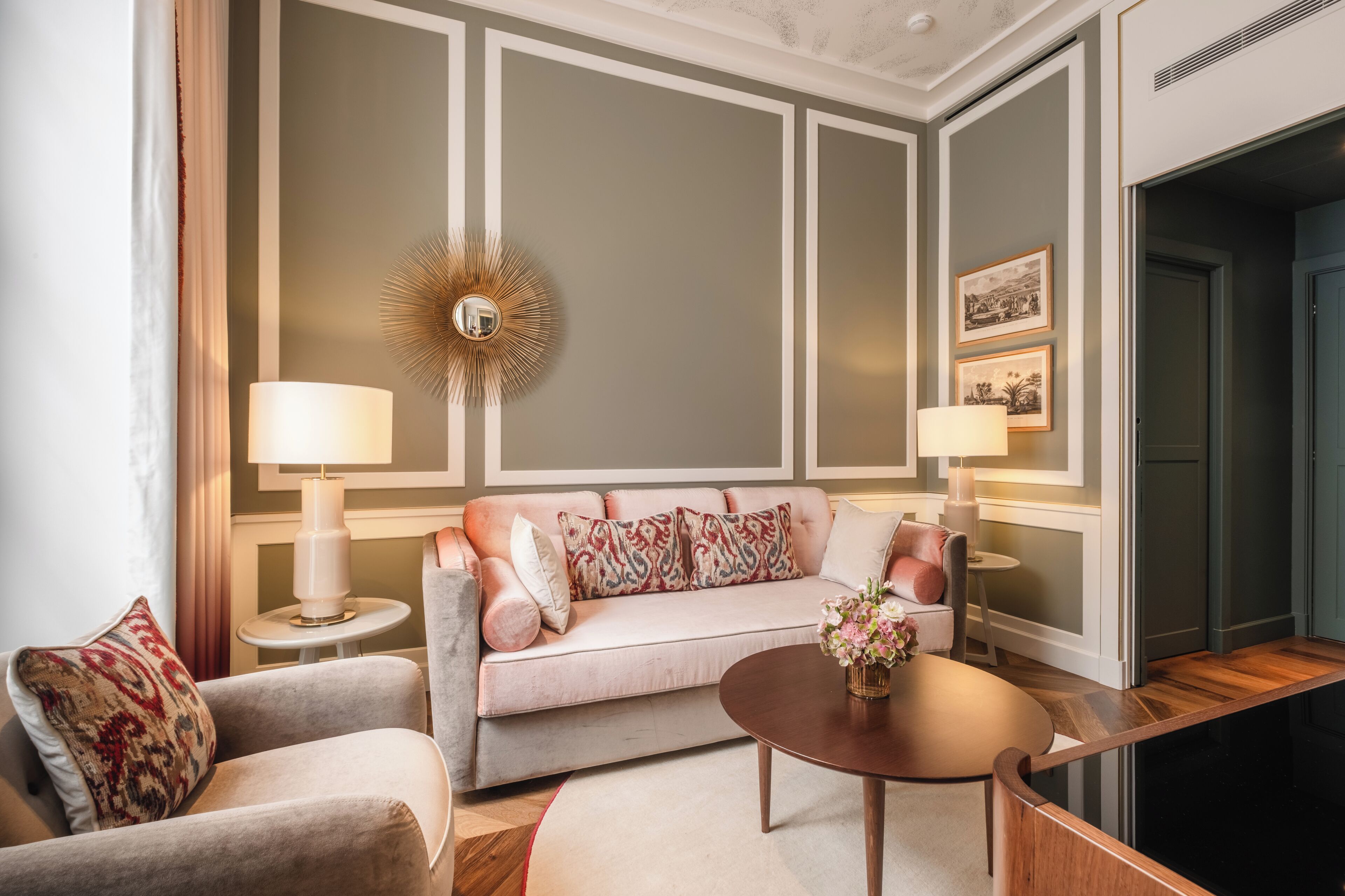 Een moderne woonkamer met een bank, twee bijzettafeltjes, een salontafel en een decoratieve spiegel.