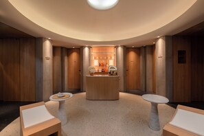 A modern spa area with a reception desk, two seating areas, and wooden paneling.
