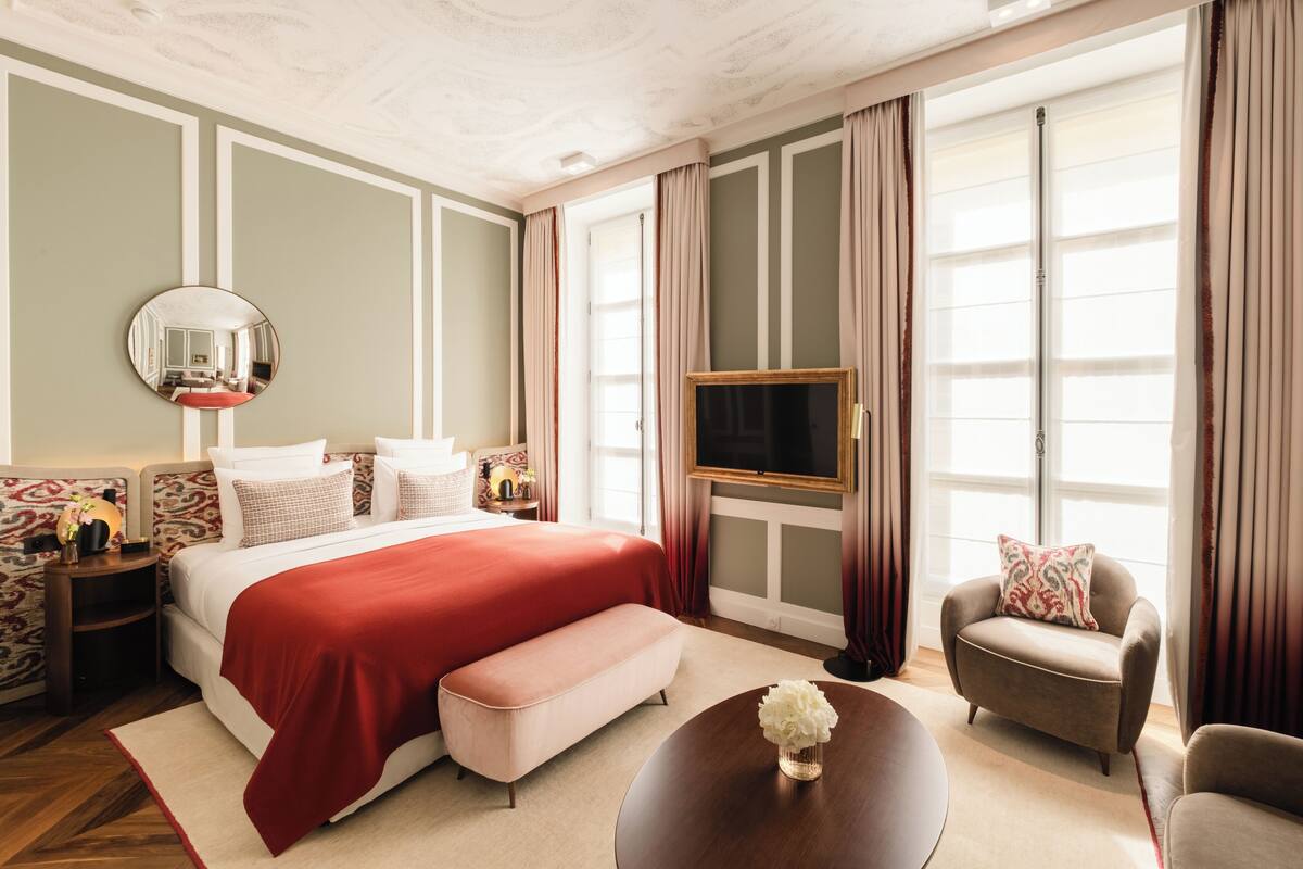 Een hotelkamer met een groot bed, een televisie, een bank en een ronde salontafel.