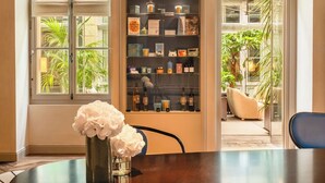 A dining area with a round table, a vase with flowers, and a glass cabinet with various items. - Hôtel Les Lumières - Relais & Châteaux  (Versailles)