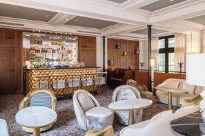 A bar area with a variety of liquor bottles, a bar counter, and seating arrangements including a sofa and multiple chairs.