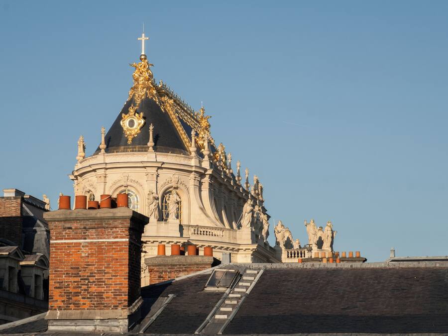 Un bâtiment historique doté d’un dôme imposant et de statues, avec un escalier menant à son entrée.