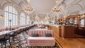 A luxurious hotel lobby with ornate chandeliers, a bar area, and seating arrangements. - Hôtel Les Lumières - Relais & Châteaux  (Versailles)