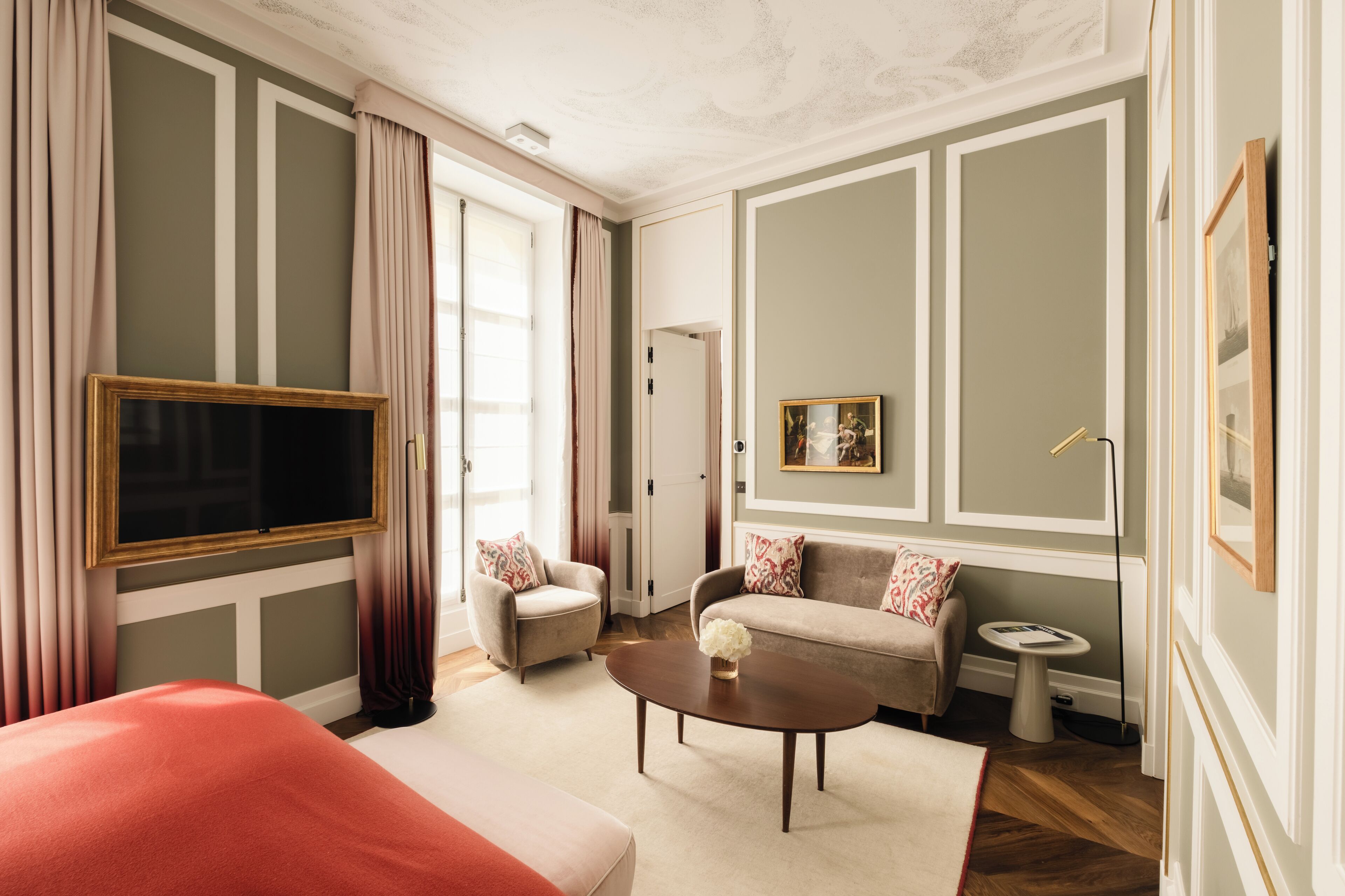 Une chambre d’hôtel avec un grand lit, un canapé, un fauteuil, une télévision, une petite table et un tableau au mur.