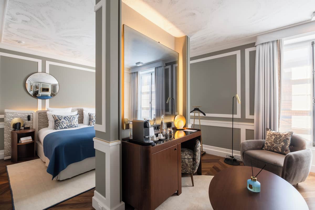 Een hotelkamer met een bed, een bureau met spiegel, een stoel en een ronde tafel.