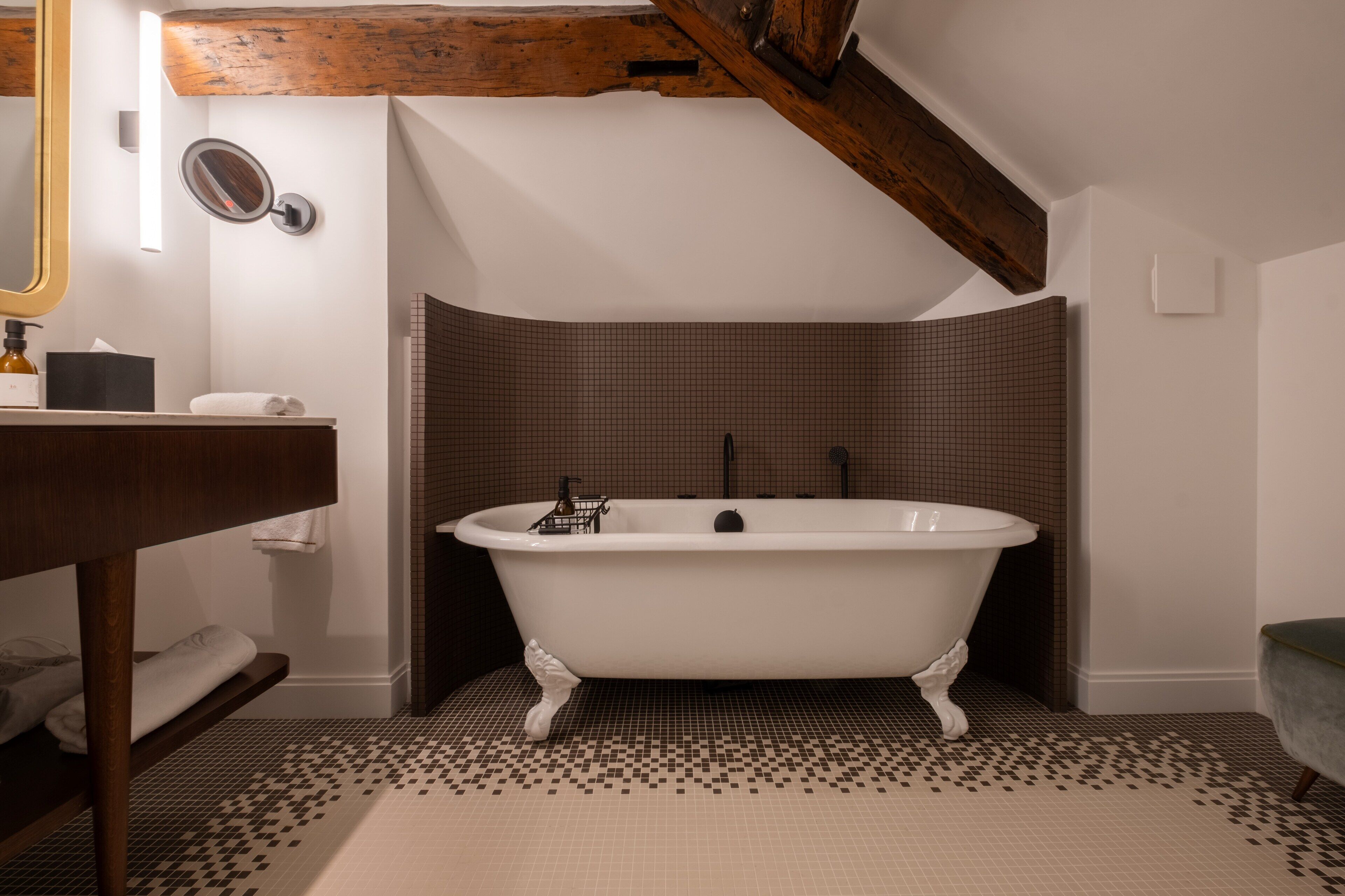 Une salle de bain avec une baignoire sur pieds, un meuble-lavabo en bois, un miroir et un sol carrelé.