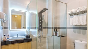 A modern bathroom with a glass-enclosed shower, a white toilet, and a vanity with a mirror and towel rack.