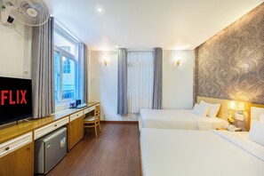 Une chambre d’hôtel équipée d’un bureau, d’une télévision, de deux lits, d’un réfrigérateur et d’une fenêtre avec des rideaux.