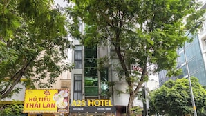 A hotel with a signboard, a street view, and a tree in front.