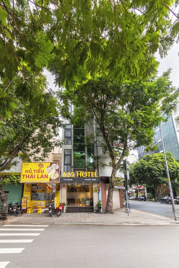 Un hôtel avec une enseigne, une vue sur la rue et un arbre devant.