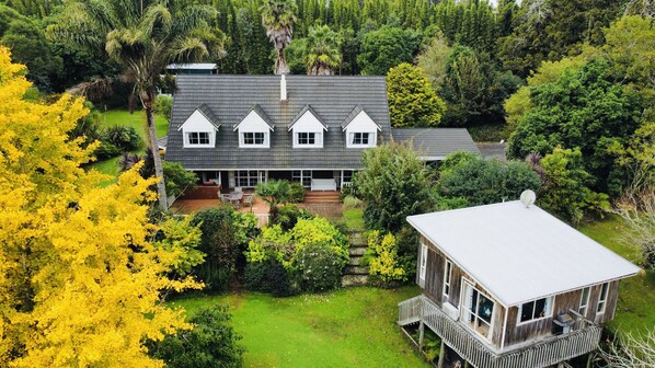 A two-story house with a large deck and a separate wooden structure on stilts. - Horse Shoe Manor. 马蹄庄园 Bay of islands. Paihia (parakara)