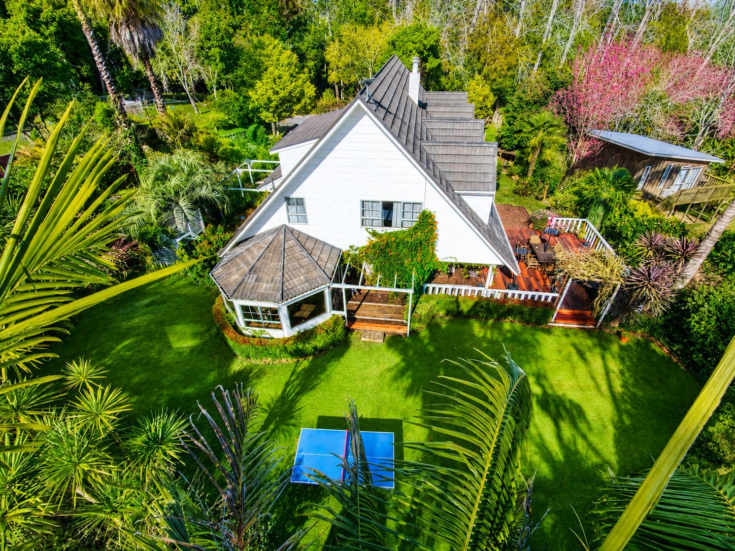 Une maison à deux étages avec un grand jardin, un patio couvert et une piscine.