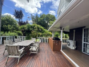 A wooden deck with a table and chairs, a barbecue grill, and a fan. - Horse Shoe Manor. 马蹄庄园 Bay of islands. Paihia (parakara)