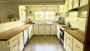 A kitchen with wooden flooring, white cabinets, a stove, and a window with a view. - Horse Shoe Manor. 马蹄庄园 Bay of islands. Paihia (parakara)