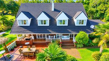 Une maison à deux étages dotée d’un patio couvert, d’une antenne parabolique et d’un jardin bien entretenu.