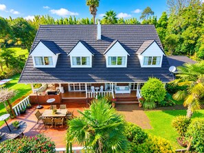 Ein zweistöckiges Haus mit überdachter Terrasse, Satellitenschüssel und einem gepflegten Garten.
