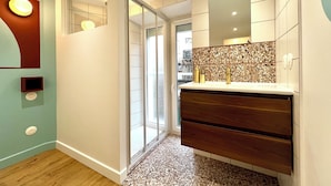 A modern bathroom with a wooden vanity, a tiled backsplash, and a glass shower enclosure.